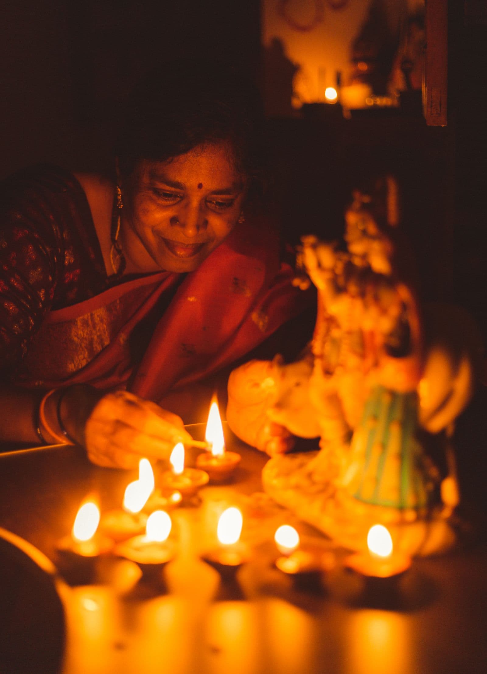 A woman lights a row of clay diya lamps